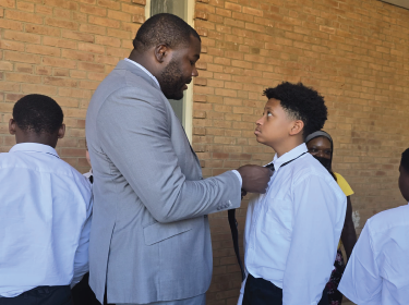 man tying tie for young student